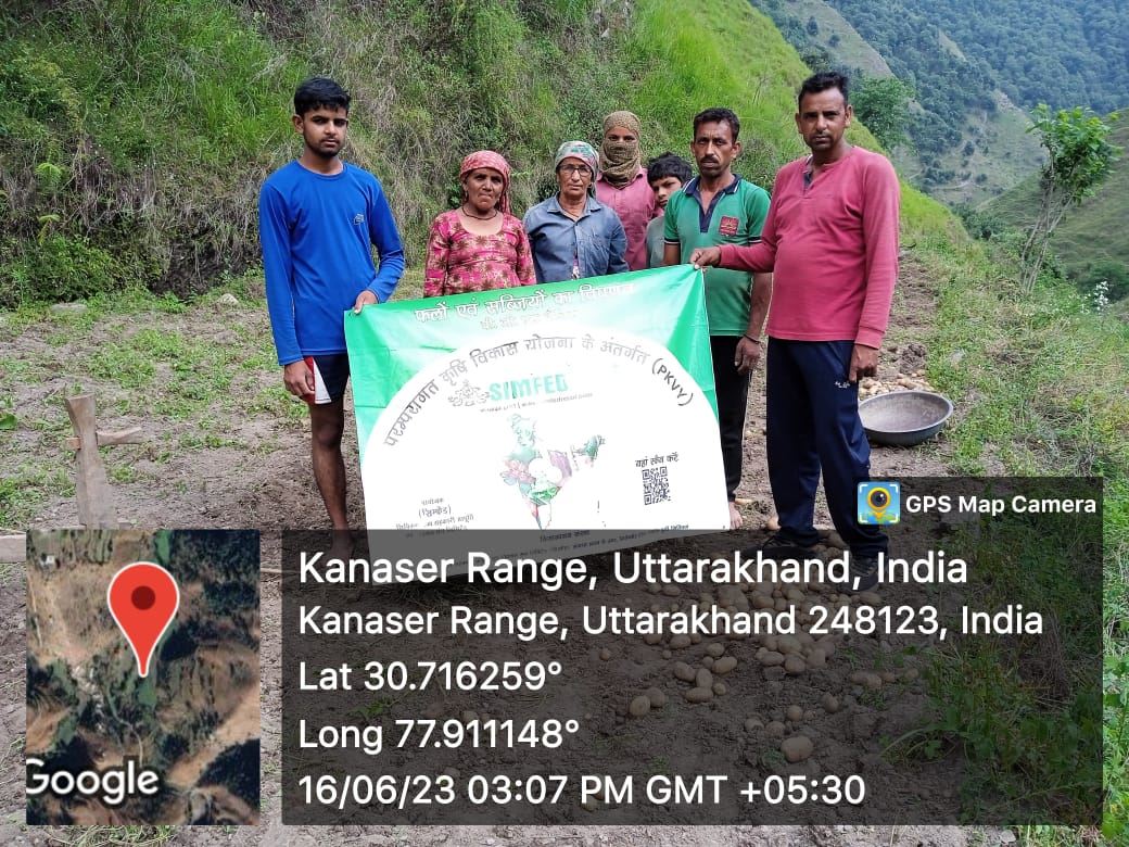 A farmer group holding a programme banner on a hillside.