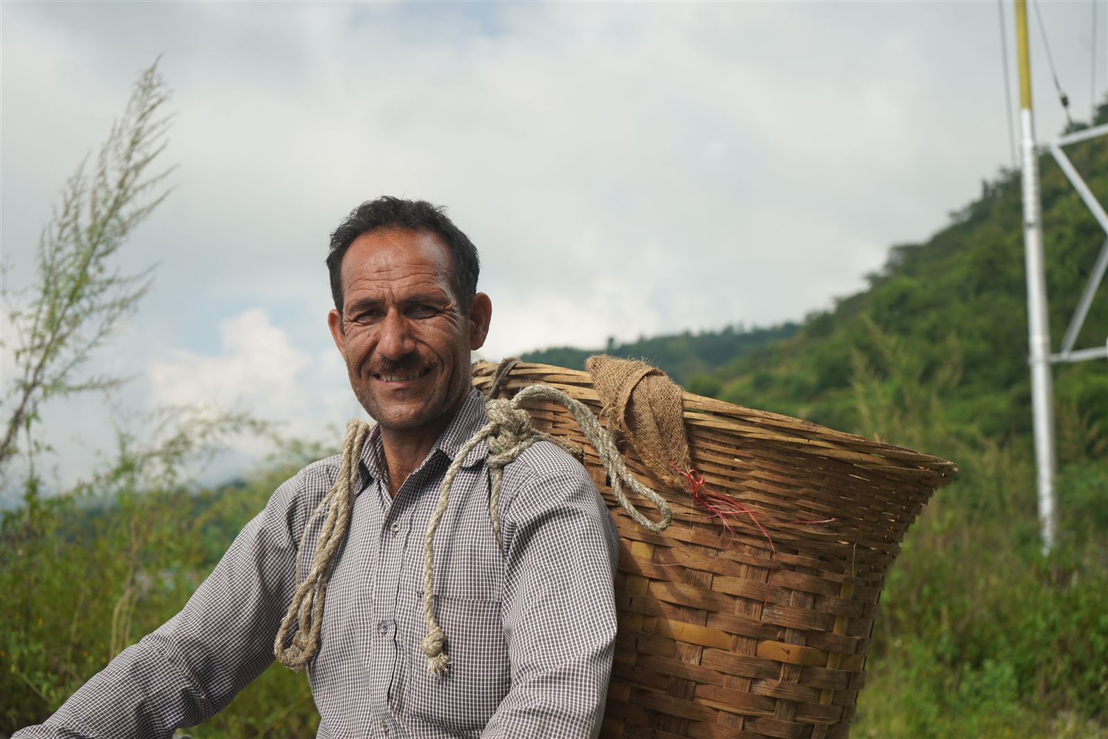 A farmer carrying a traditional conical cane basket on his back.