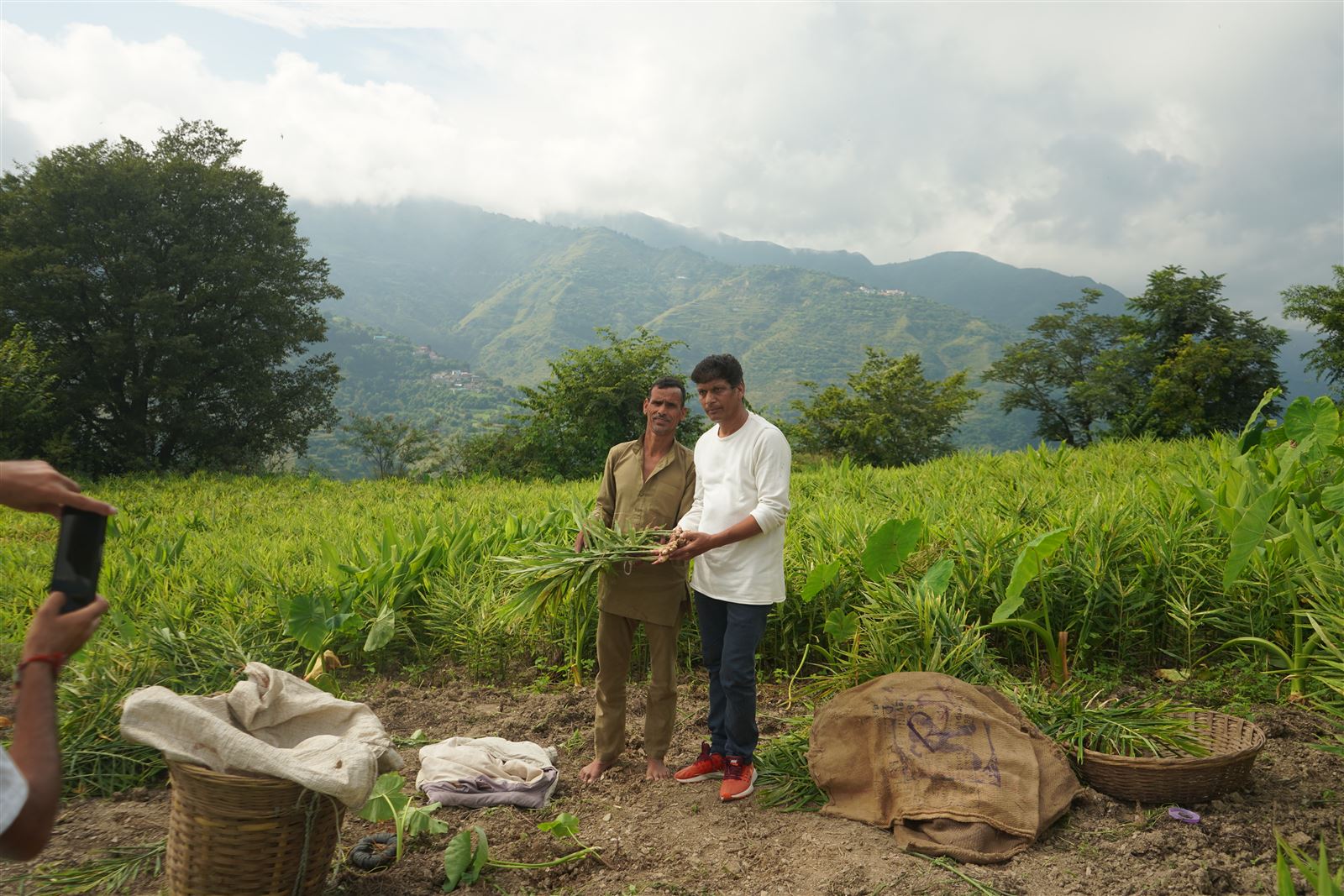 Farmers standing in a field with forested hills behind.